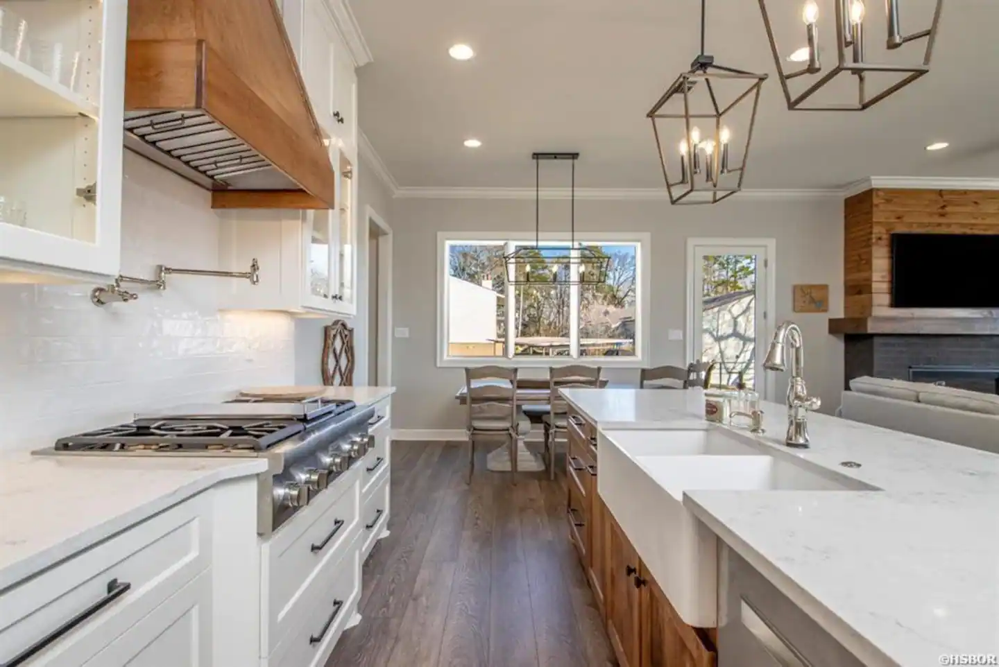 A kitchen with white cabinets , a stove , a sink and a fireplace.