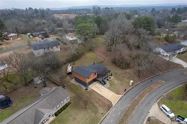 An aerial view of a house in a residential area surrounded by trees.