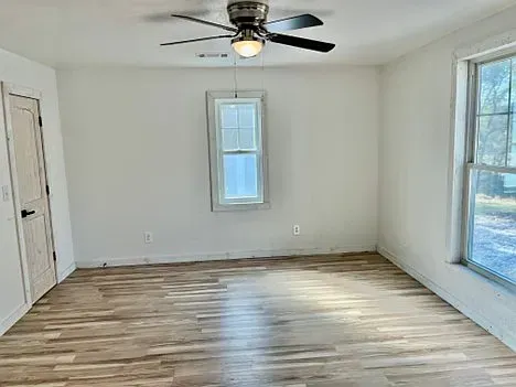 An empty room with hardwood floors and a ceiling fan.