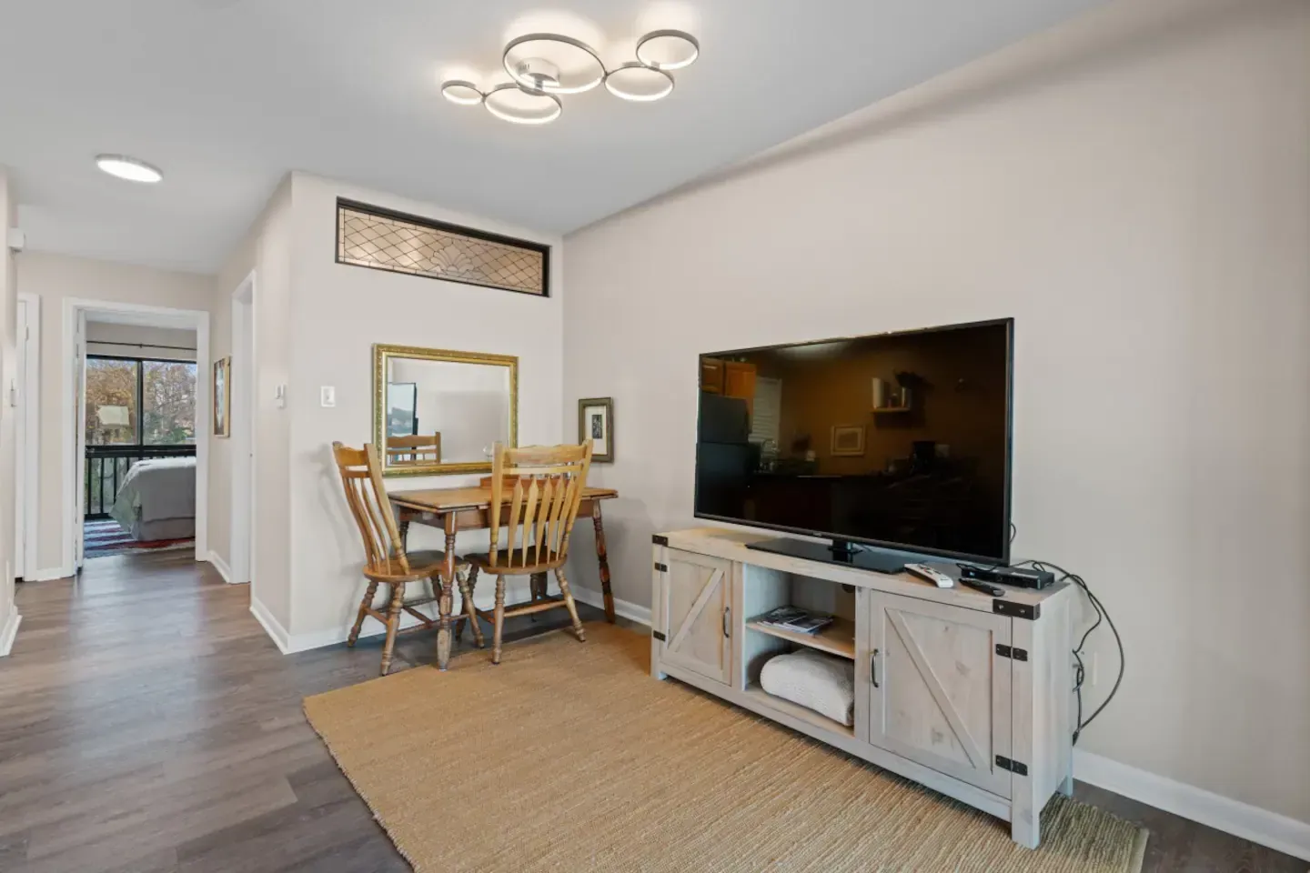 A living room with a table and chairs and a flat screen tv.