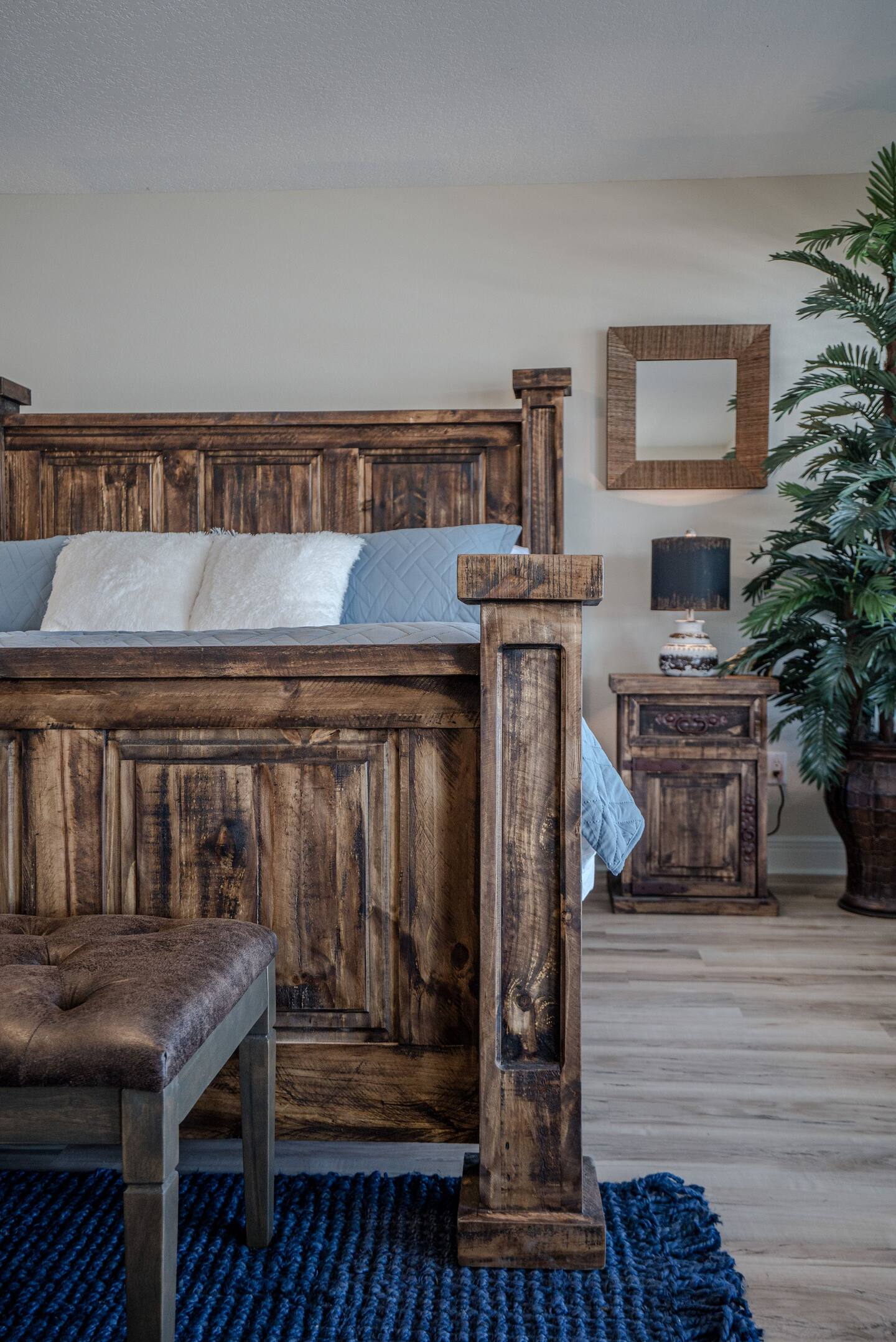A bedroom with a wooden bed , nightstand , and bench.