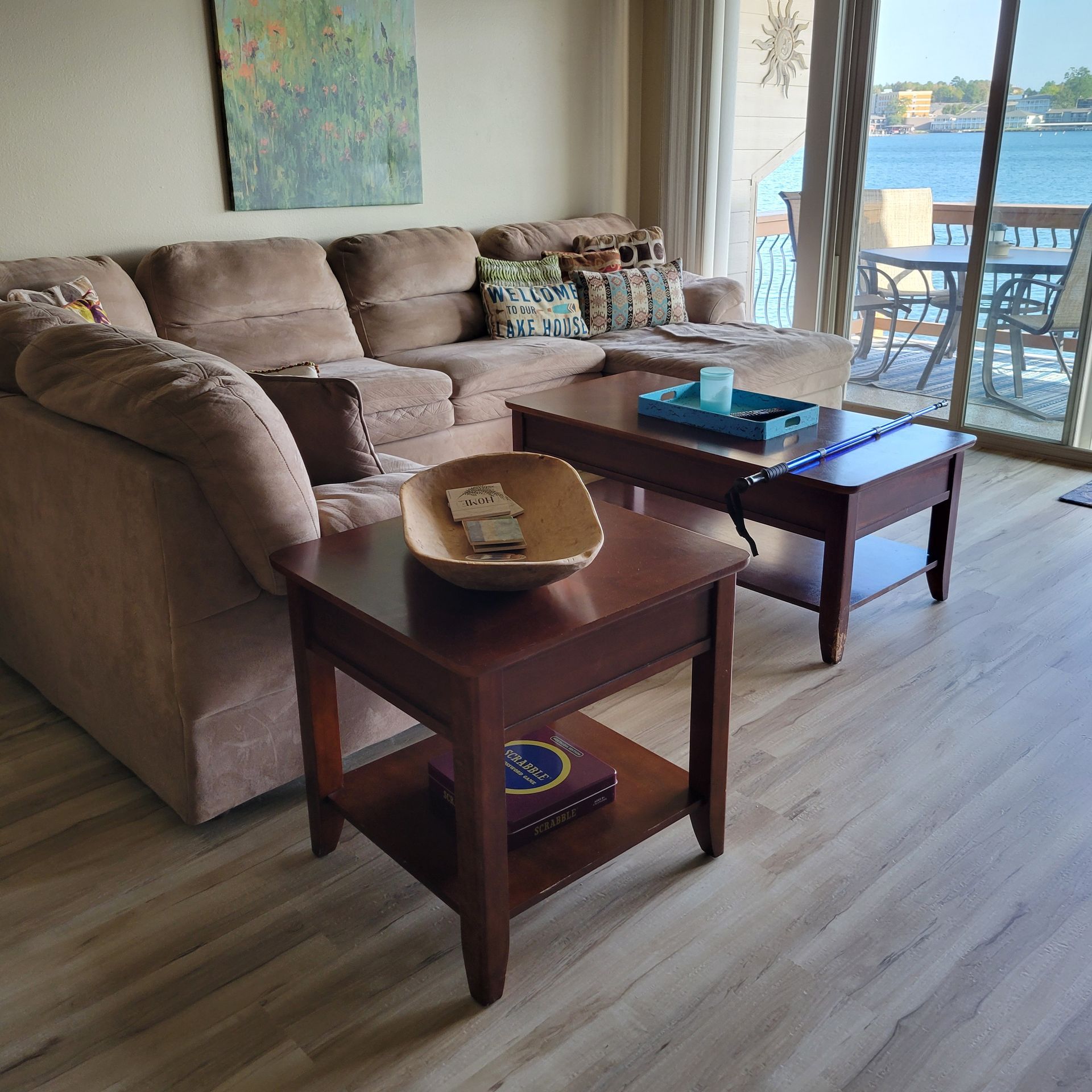 Living room with a tan sectional sofa, dark wood side tables, and a view of water.