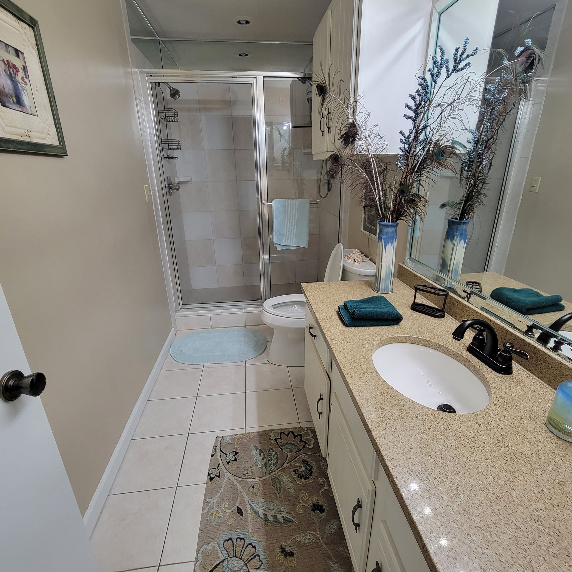 Bathroom with shower, vanity, and toilet. Beige walls, granite countertop, beige tile floor.