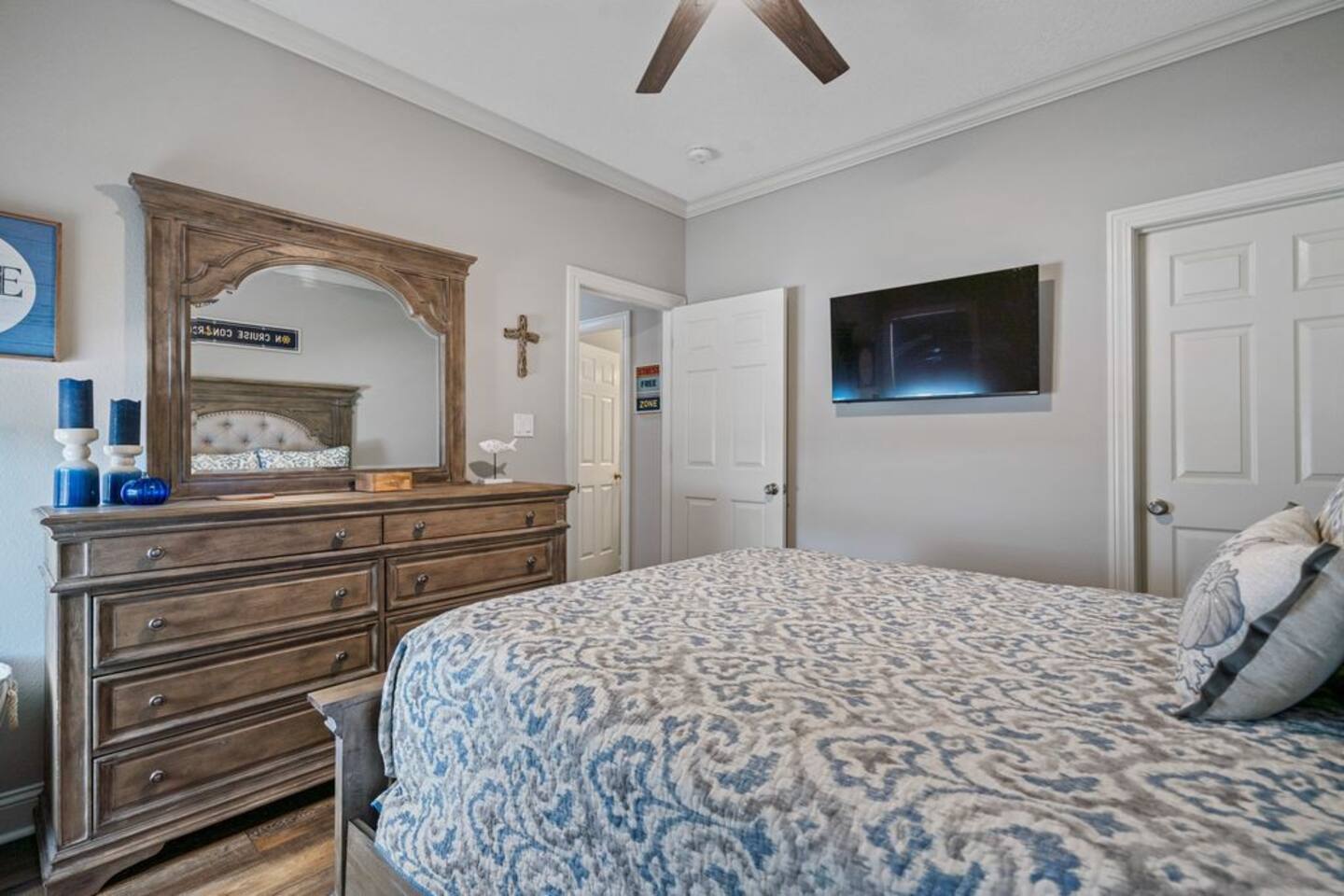 A bedroom with a bed , dresser , mirror and television.