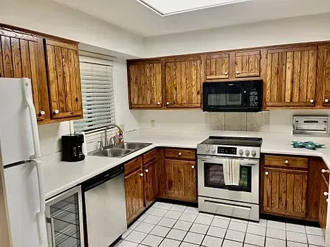 Kitchen with wooden cabinets, white countertops, stainless steel appliances, and tiled floor.