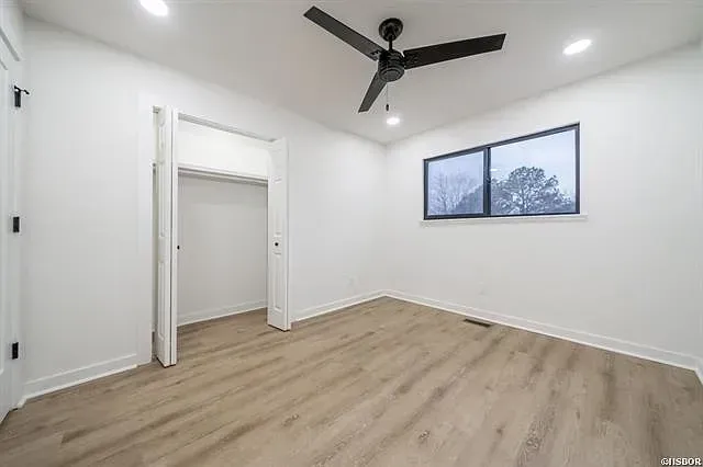 An empty bedroom with a ceiling fan and a window.