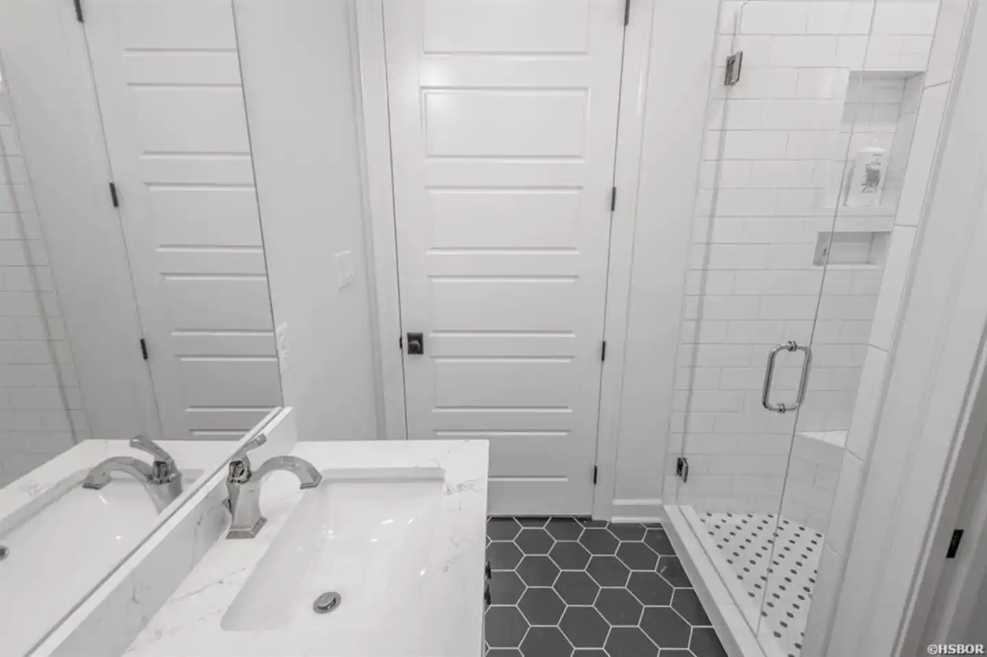 A bathroom with a sink , mirror and shower.