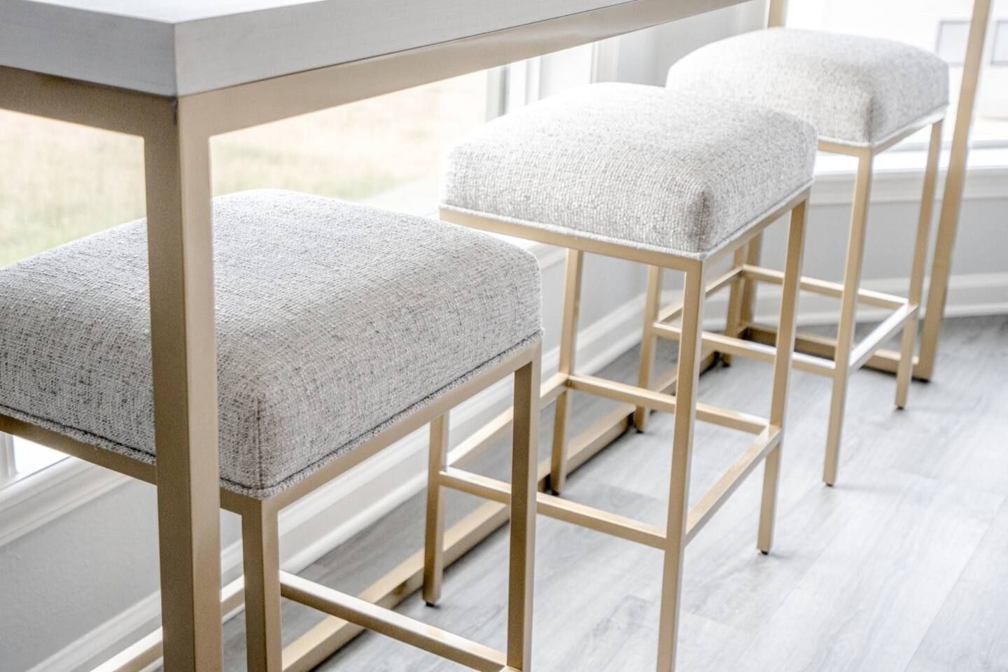 Three white bar stools are sitting next to a white table.