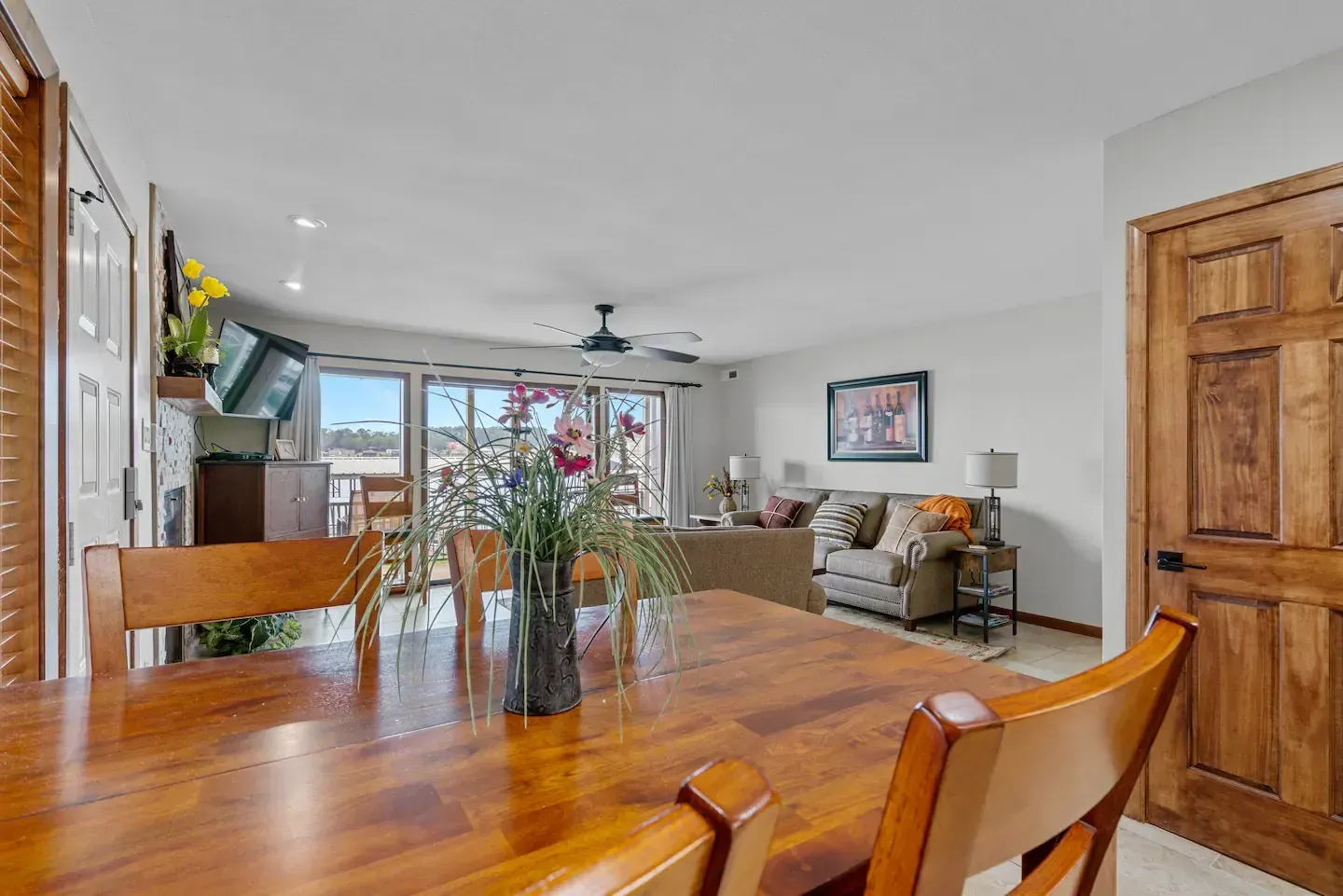 A dining table and chairs in a living room with a vase of flowers on it.