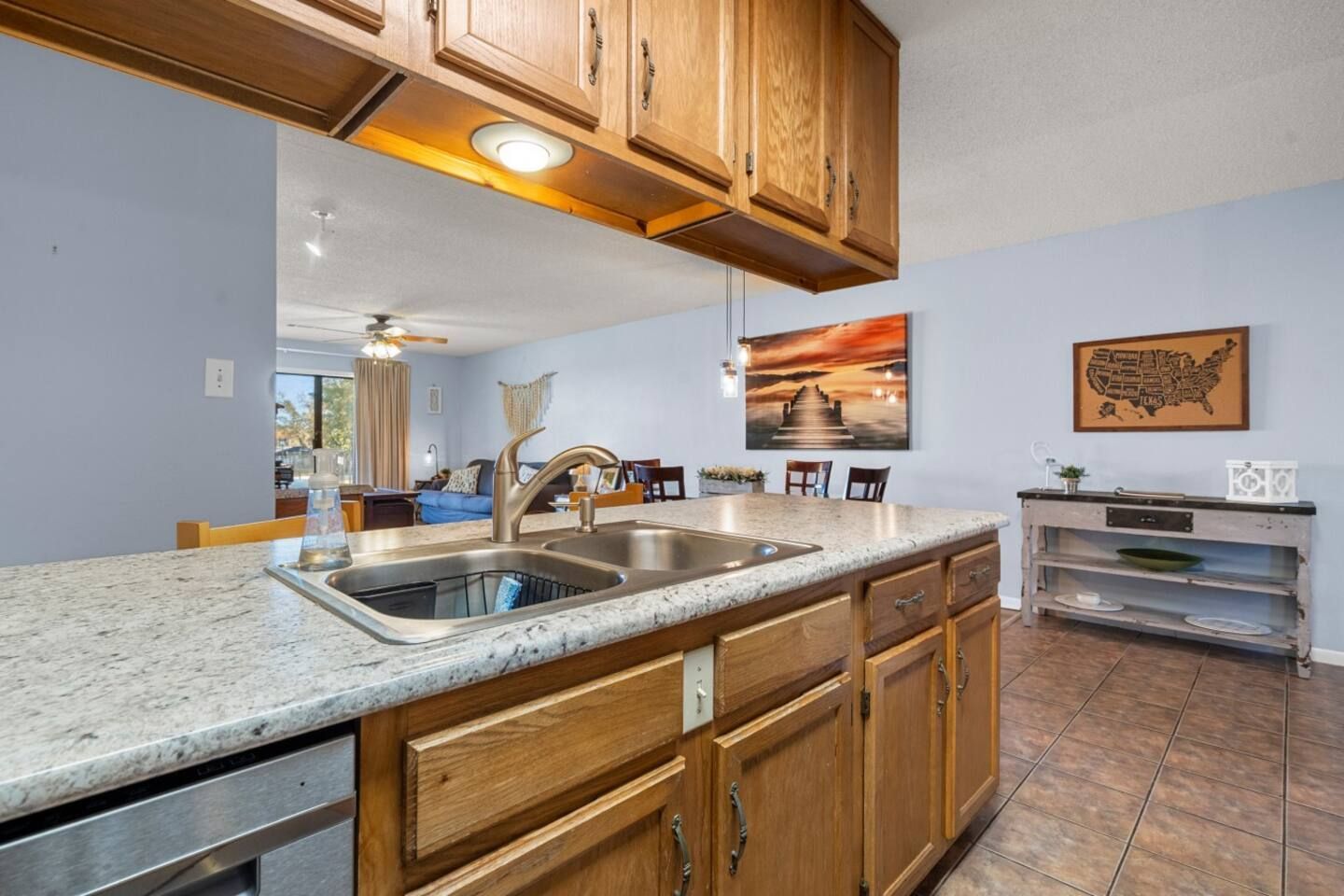 A kitchen with wooden cabinets , granite counter tops , a sink and a dishwasher.