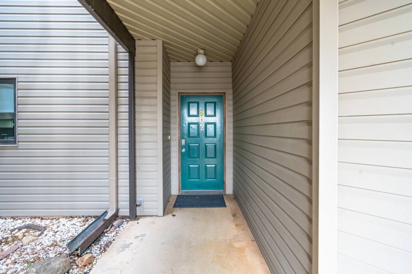 There is a blue door in the middle of a hallway between two buildings.