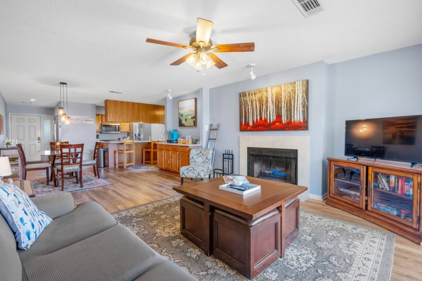 A living room with a couch , coffee table , television and fireplace.