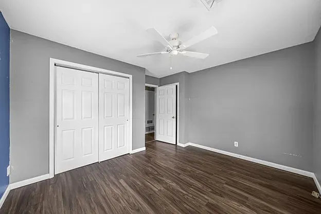 An empty bedroom with hardwood floors and a ceiling fan.