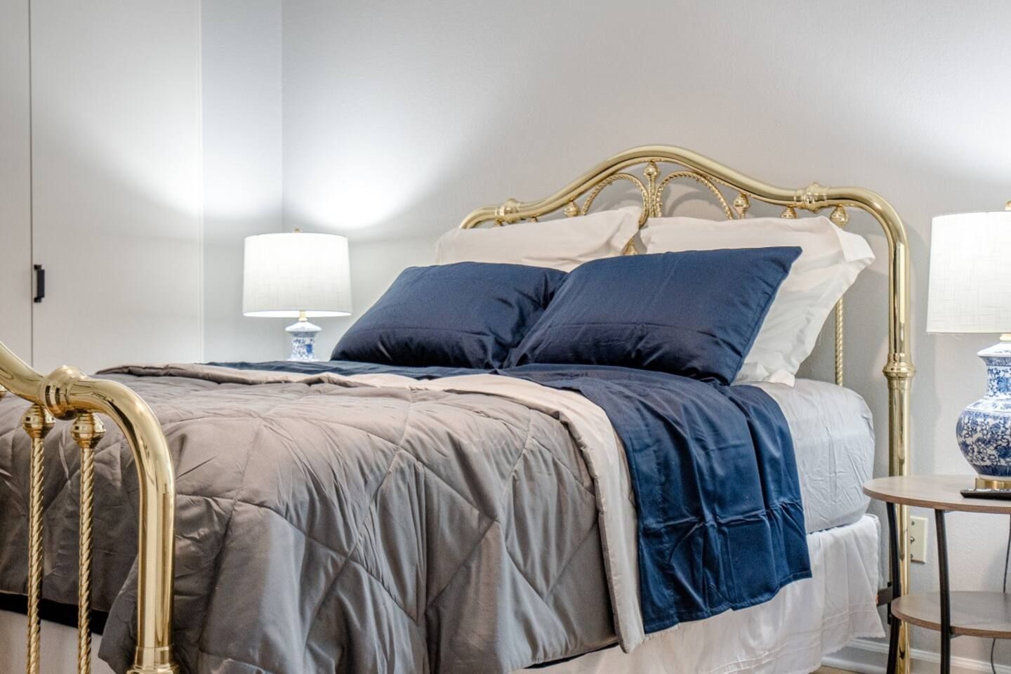 A bedroom with a bed , two lamps and a nightstand.