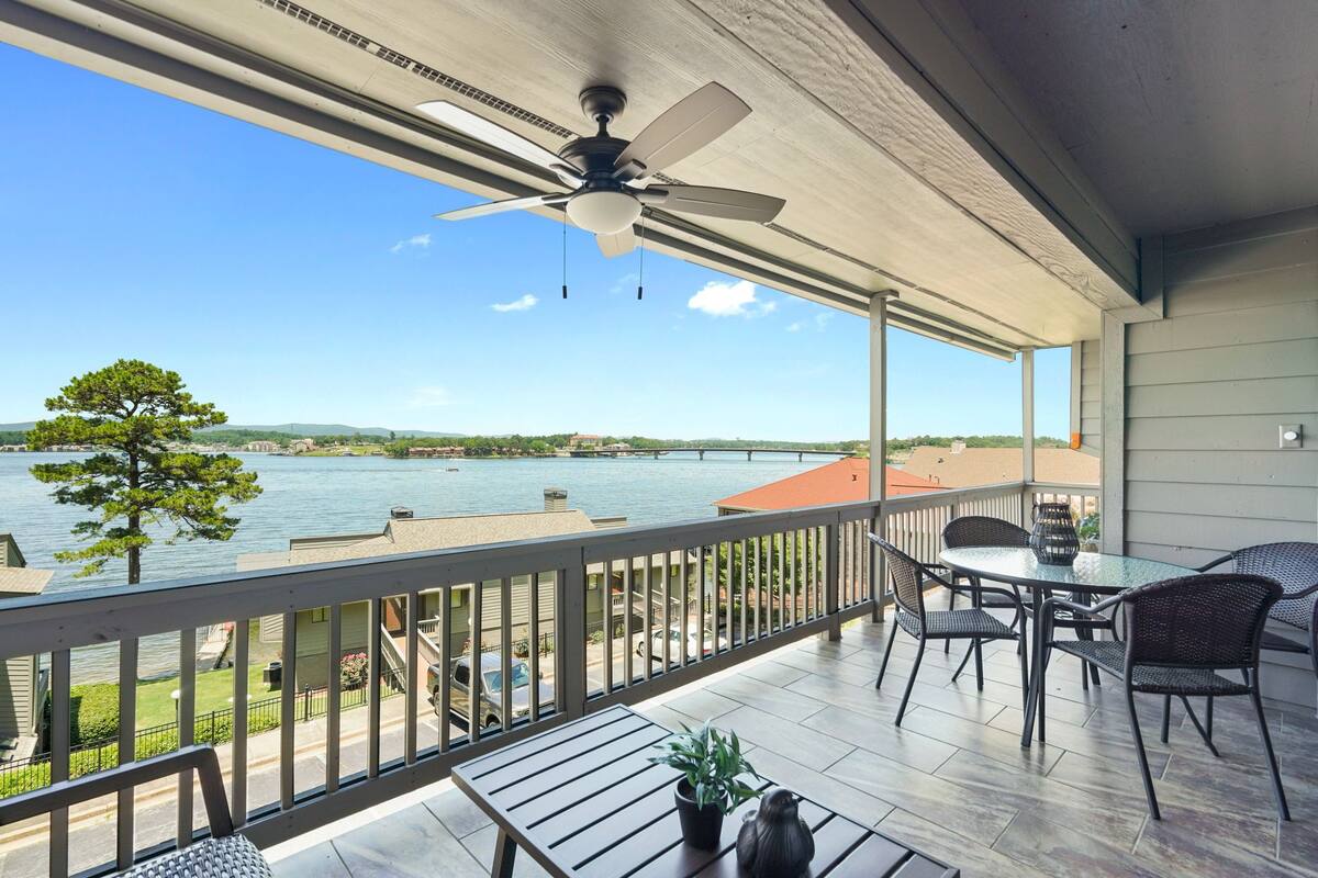 A balcony with a view of a lake and a ceiling fan.