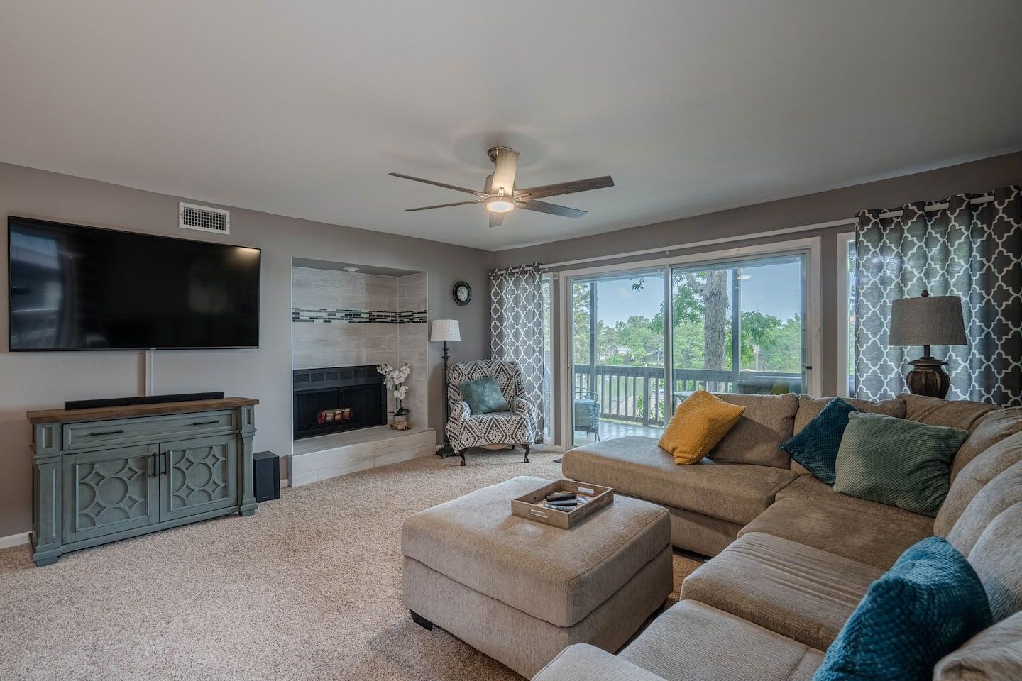 A living room with a couch , ottoman , television and fireplace.