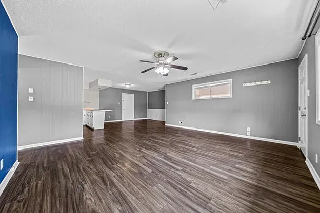 An empty living room with hardwood floors and a ceiling fan.