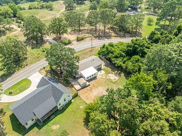 An aerial view of a house surrounded by trees and a road.