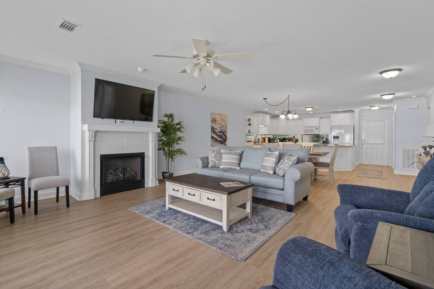 A living room with a couch , chairs , coffee table , fireplace and television.