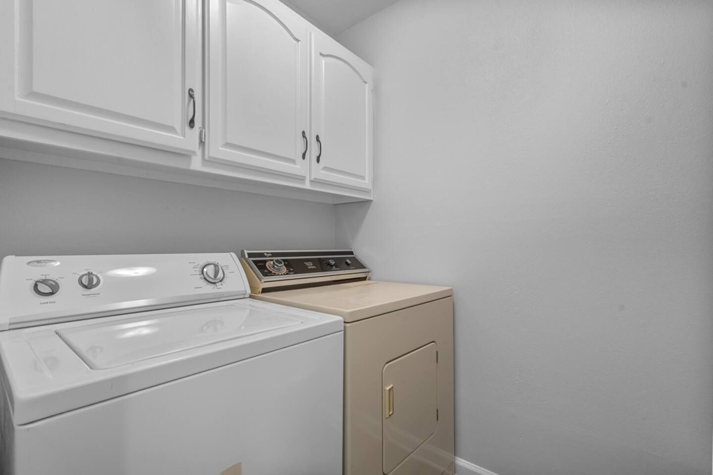 A laundry room with a washer and dryer and white cabinets.
