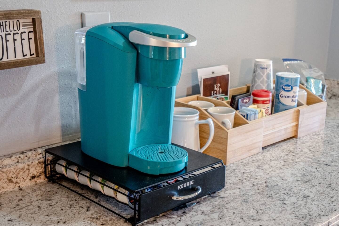 A blue coffee maker is sitting on a counter next to a tray of coffee.