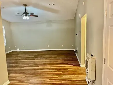 An empty living room with hardwood floors and a ceiling fan.