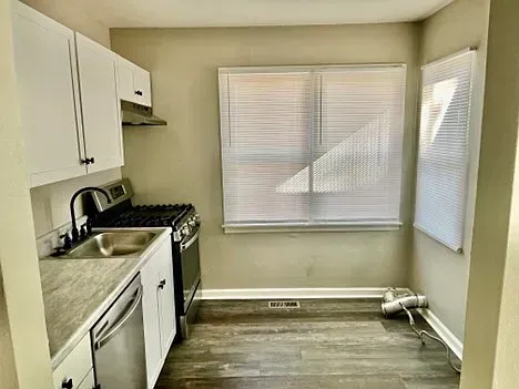 A kitchen with a stove , sink , dishwasher and window.