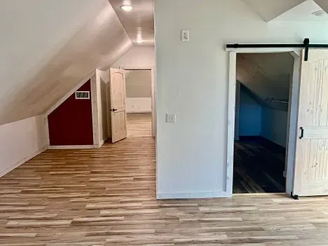 An empty room with hardwood floors and a sliding barn door.