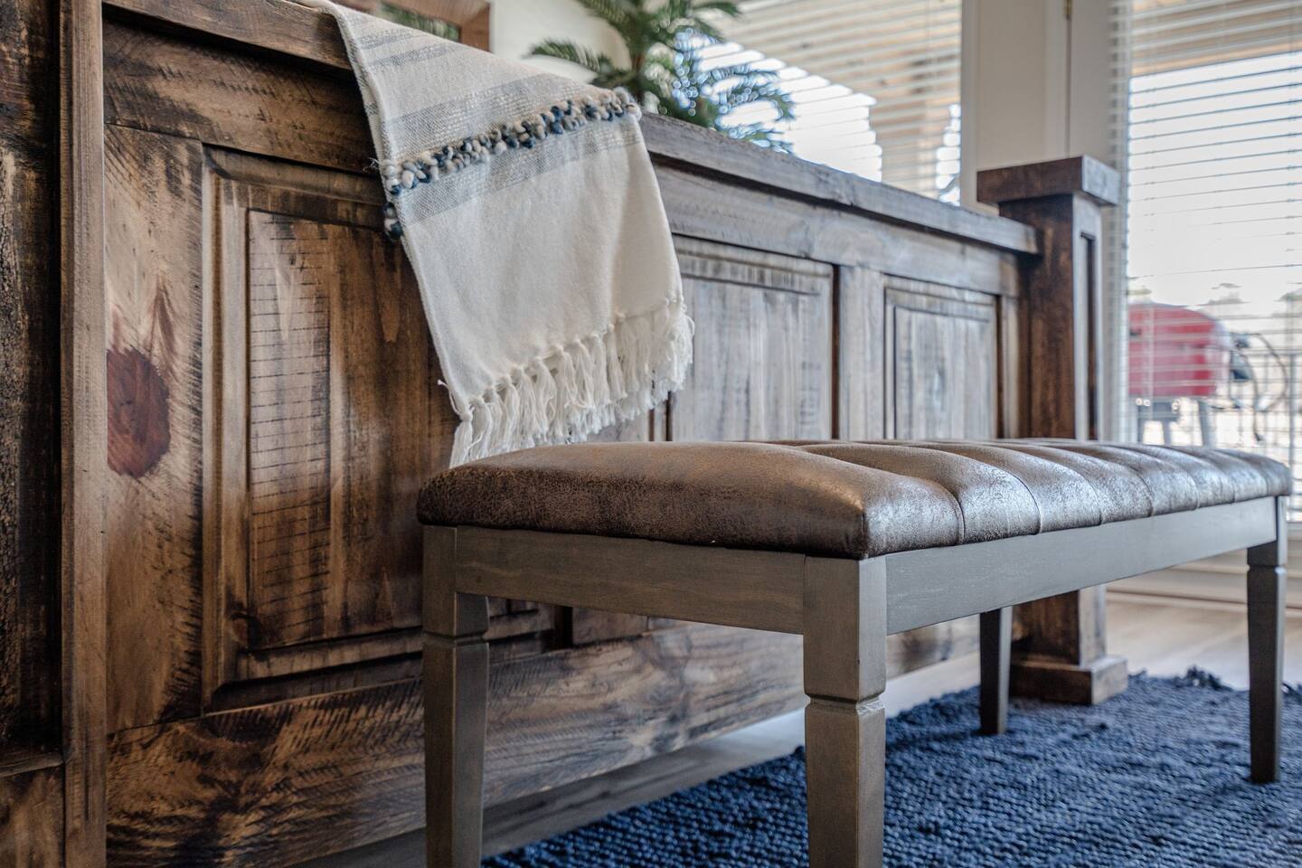 A bench with a blanket on it is sitting next to a wooden counter.