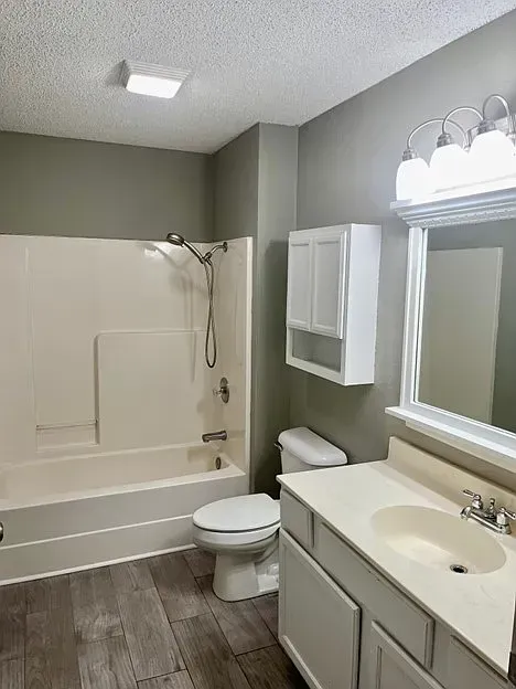 A bathroom with a toilet , sink , bathtub and mirror.