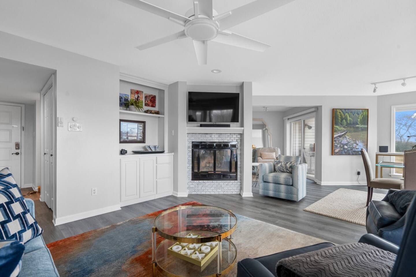 A living room filled with furniture and a fireplace with a ceiling fan.