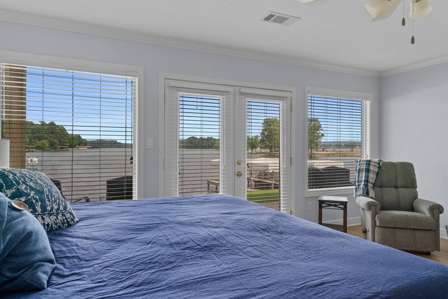A bedroom with a bed , chair , and lots of windows.