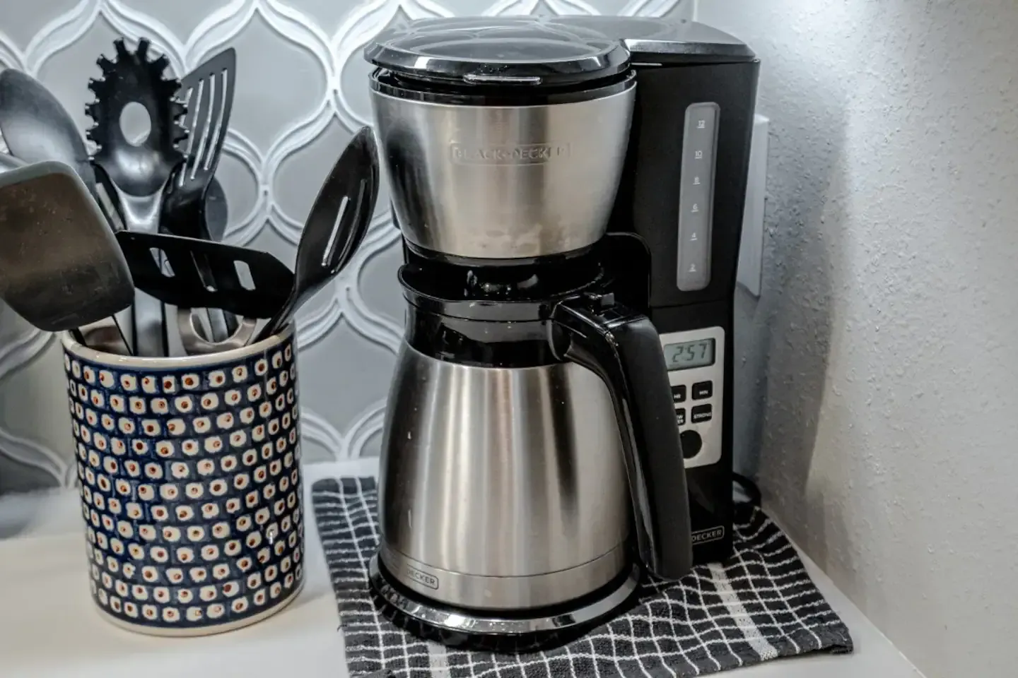 A coffee maker is sitting on a counter next to a utensil holder.