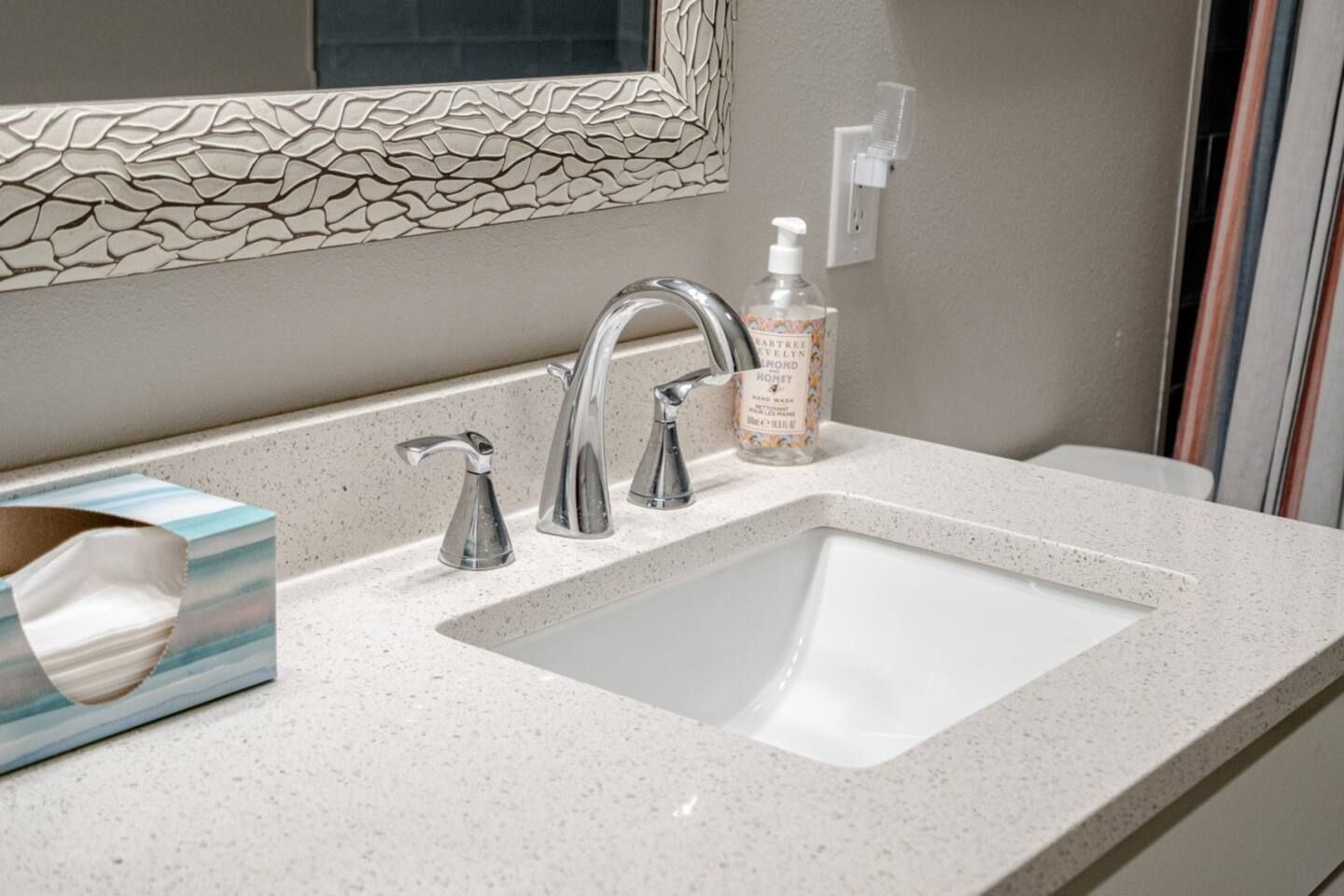 A bathroom sink with a soap dispenser and a mirror.