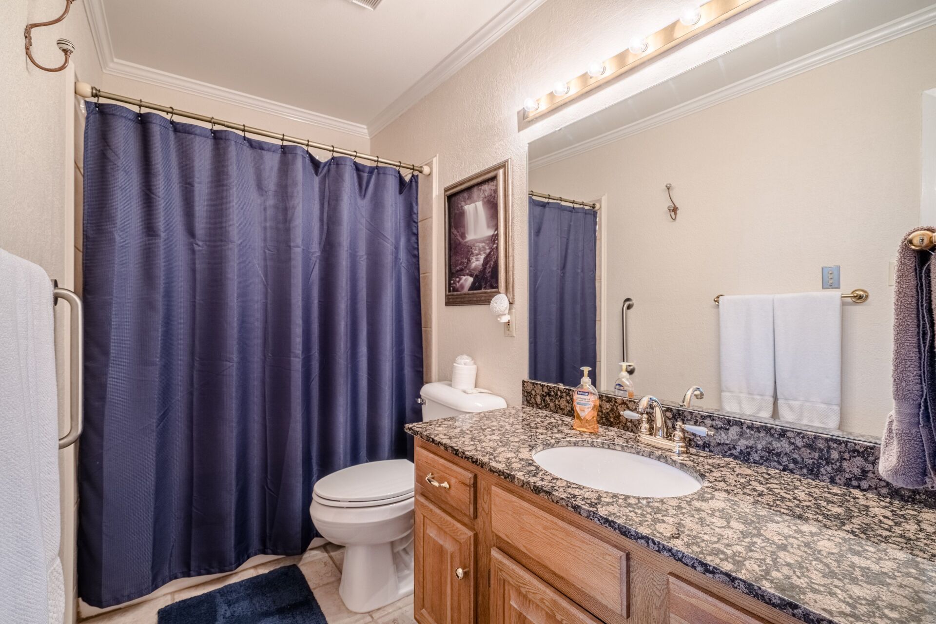 A bathroom with a toilet , sink , mirror and shower curtain.