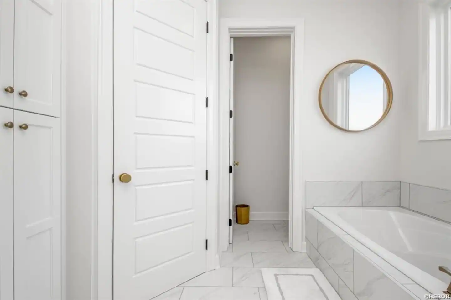 A bathroom with a tub , mirror , and closet.