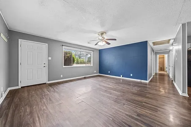 An empty living room with hardwood floors and a ceiling fan.