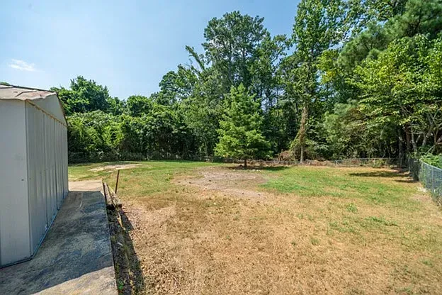 A large yard with a shed and trees in the background.