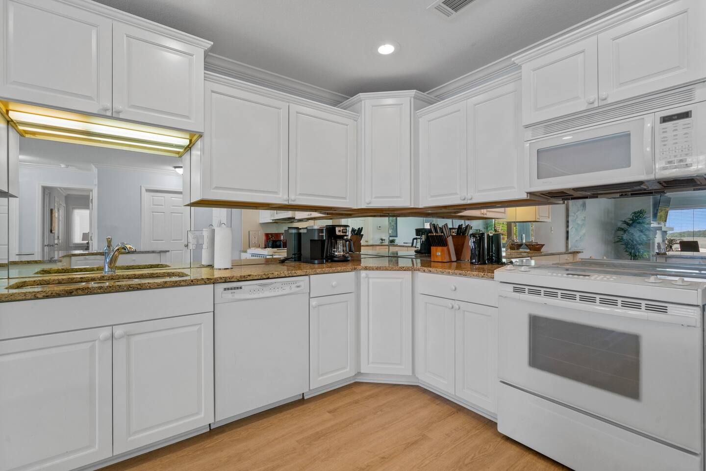 A kitchen with white cabinets , a stove , a sink , and a microwave.