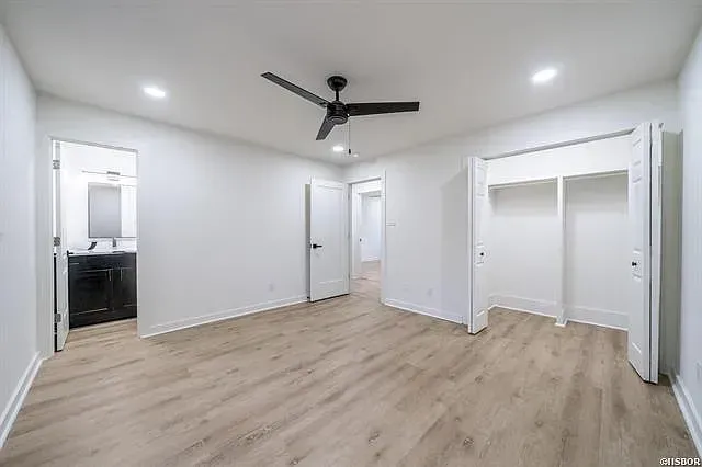 An empty bedroom with hardwood floors and a ceiling fan.