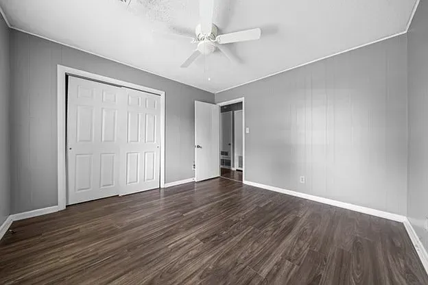 An empty bedroom with hardwood floors and a ceiling fan.