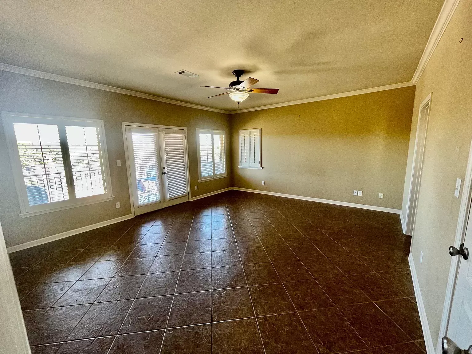 A large empty room with a ceiling fan and lots of windows.