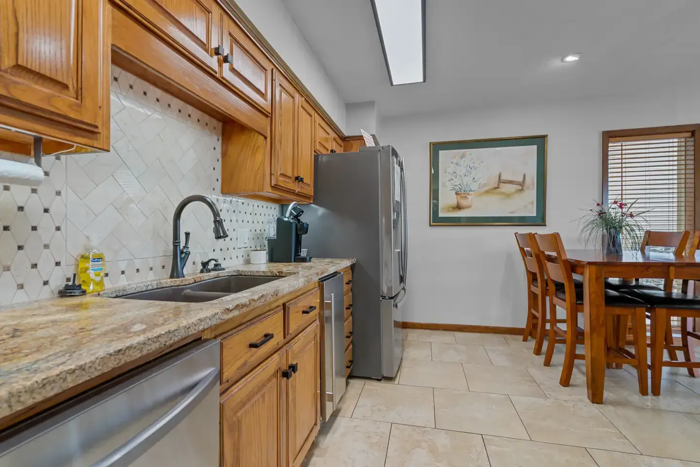 A kitchen with a sink , refrigerator , dishwasher , and dining table.