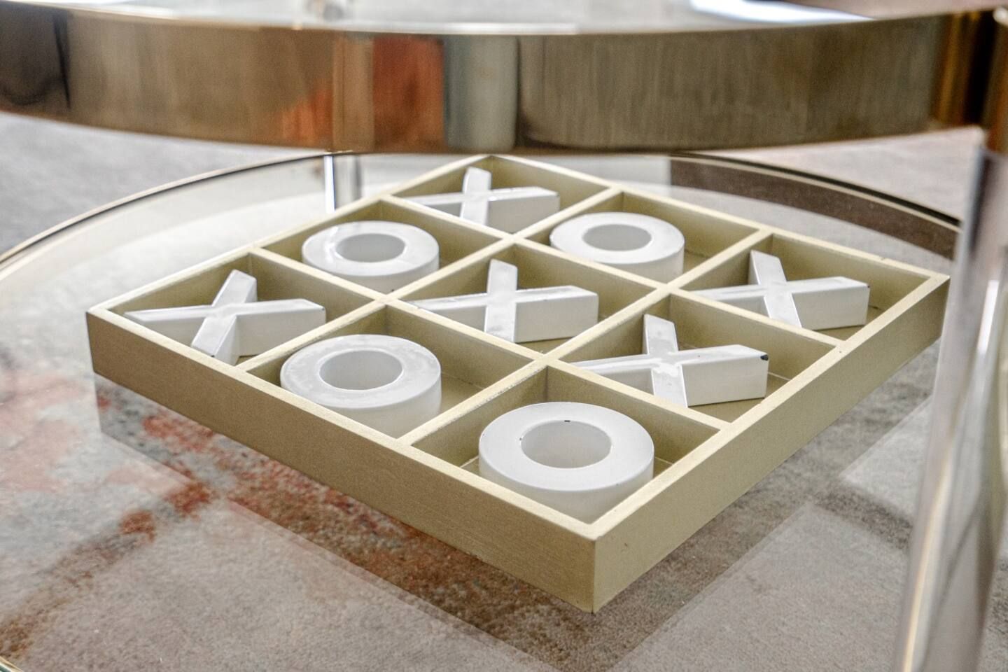 A tic tac toe game is sitting on a glass table