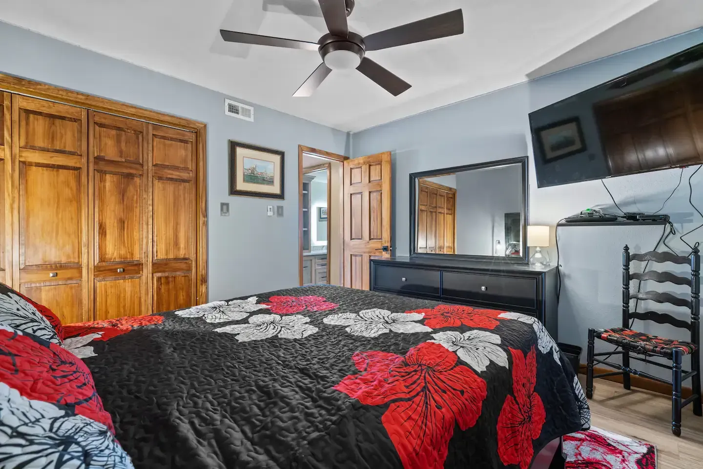 A bedroom with a bed , dresser , mirror and ceiling fan.