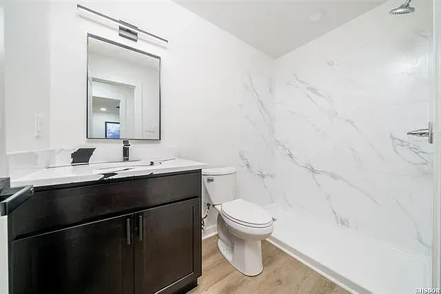 A bathroom with a toilet , sink , mirror and shower.