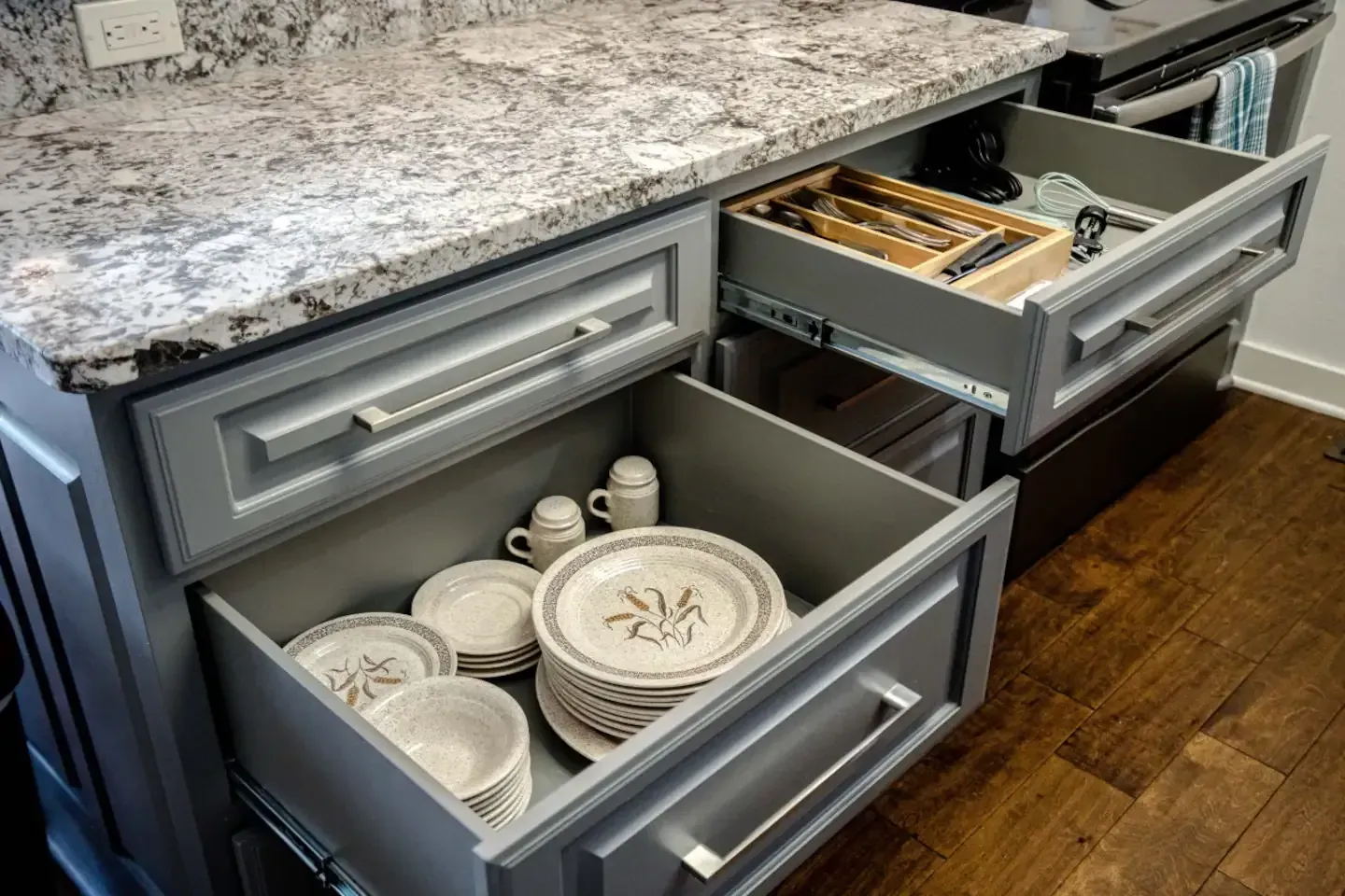 A kitchen with a lot of drawers filled with plates and cups.