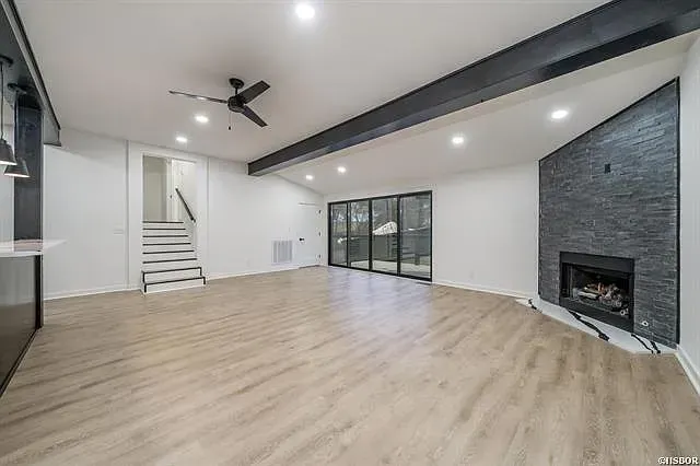 An empty living room with hardwood floors and a fireplace.