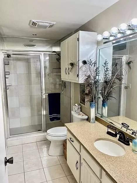 A bathroom with a toilet , sink , shower and mirror.