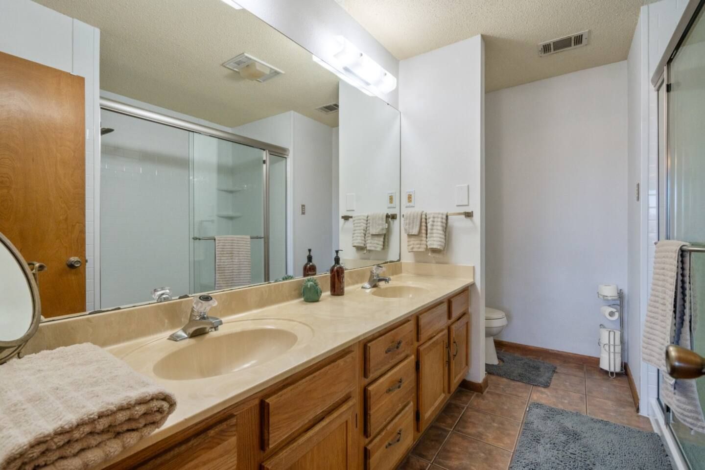 A bathroom with two sinks , a toilet , and a large mirror.